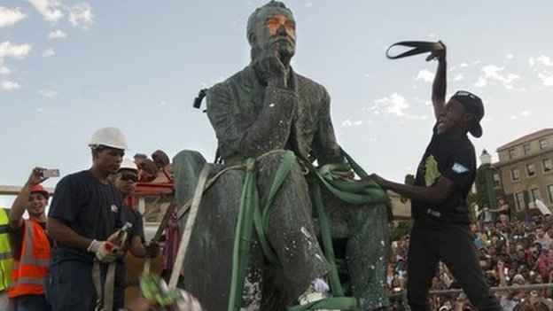 Students attack the defaced statue of British mining magnate and politician, Cecil John Rhodes, as it is removed by a crane from its position at the University of Cape Town on April 9, 2015, in Cape Town