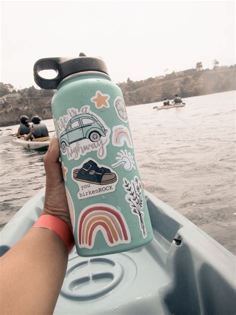 someone is holding up a water bottle with stickers on it while in a kayak