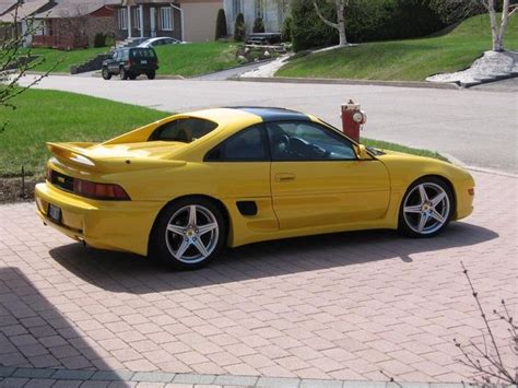 a yellow sports car parked in front of a red fire hydrant on a brick ...