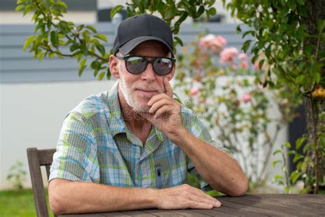 Senior Man in Baseball Cap with Sunglasses Relaxing in the Garden Stock ...