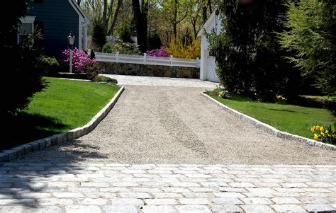 a driveway leading to a house with trees and flowers