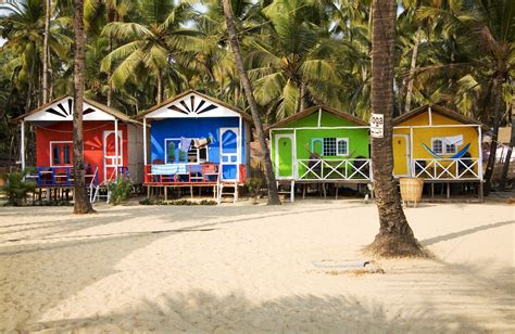 several colorful beach huts on the sand near palm trees