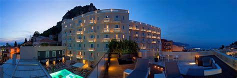 an outdoor swimming pool at night next to a building with lit up ...