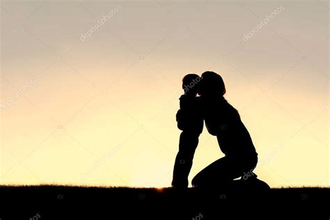 Silhouette of Young Mother Hugging Toddler Son at Sunset Stock Photo by ...