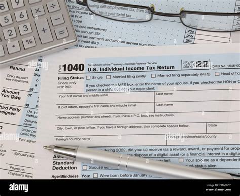 An IRS 1040 tax year 2022 form is shown, along with an ink pen ...