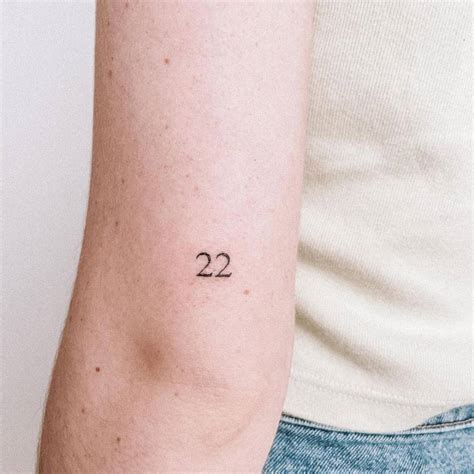 "22" lettering tattoo on the tricep.