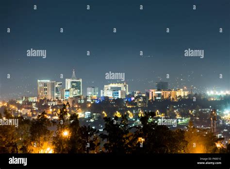 A wide view of Kigali city skyline lit up at night, under a deep blue ...