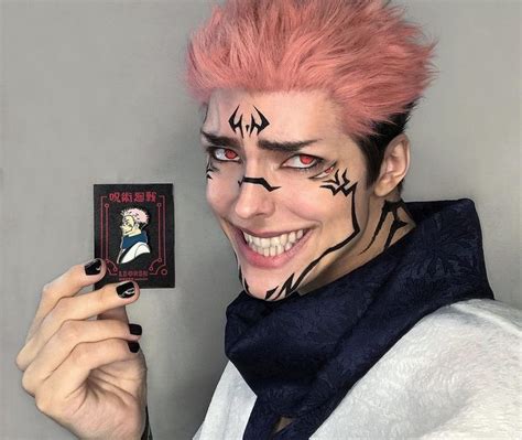 a person with pink hair and makeup holding up a card