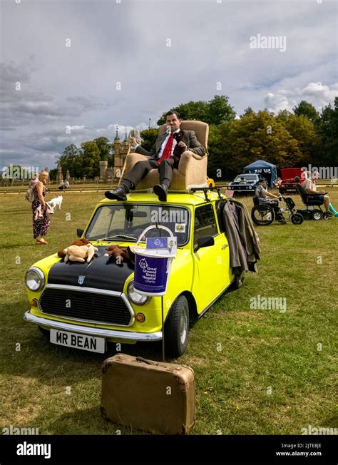 Mr. Bean lookalike sitting in an armchair on top of yellow mini classic ...