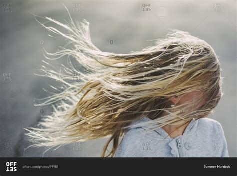 A blonde girl's hair blowing in the wind, obscuring her face stock ...