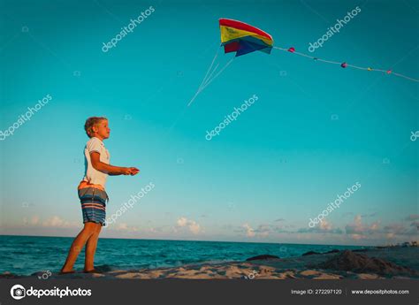 Young boy flying a kite on tropical beach at sunset Stock Photo by ...