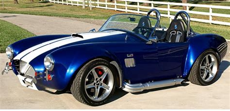 a blue and white sports car parked in front of a fence