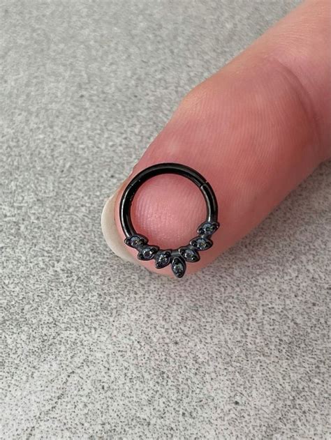 a person's finger with a black ring on top of their thumb and an object ...