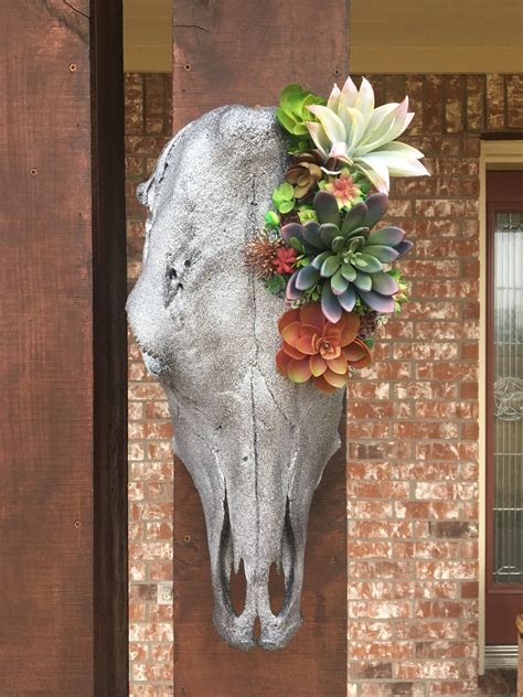 a cow's skull with succulents and flowers on the side of it