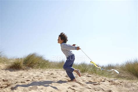 Young boy flying kite on beach — leisure, escape - Stock Photo | #167878904