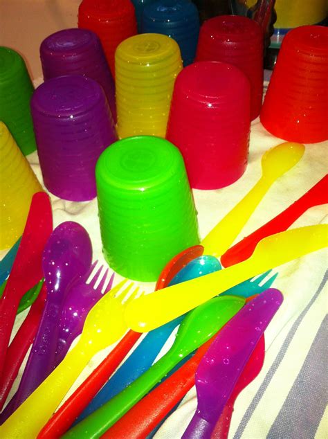 many different colored plastic utensils on a table