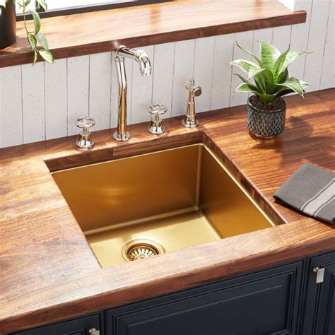 a kitchen sink sitting on top of a wooden counter next to a potted plant