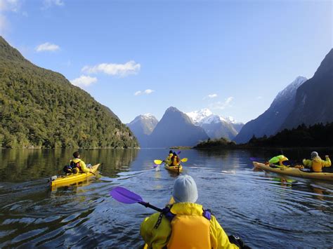 several people in yellow kayaks paddling on the water with mountains in ...