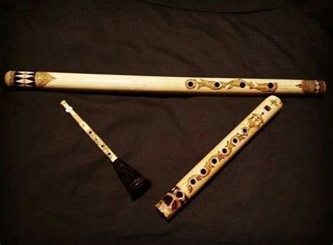 two flutes are laying next to each other on a black sheet with gold and ...