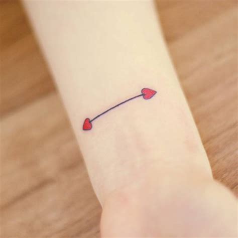 Double headed arrow tattoo on the left wrist, with