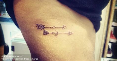 Side tattoo of two arrows by André de Camargo.