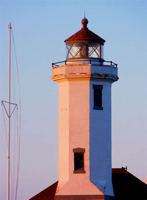 a white lighthouse with a brown roof and a wind indicator on it's side