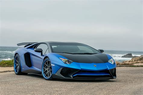 Blue and black Lamborghini Gallardo parked on gray sand near ocean ...