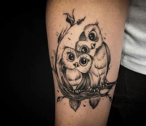 an owl tattoo on the arm with two small owls sitting on it's back