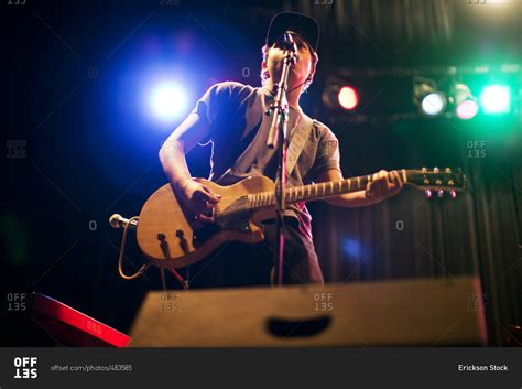 Teenage boy singing and playing guitar on stage stock photo - OFFSET