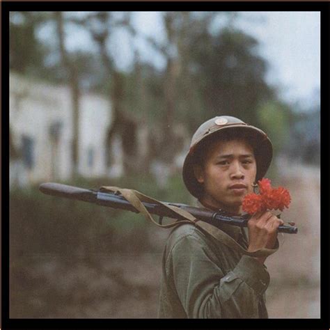 A Vietnamese soldier holding a flower with his rifle during the march ...