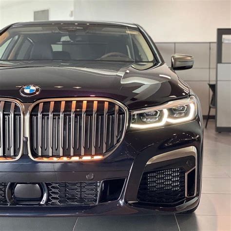 the front end of a black bmw car in a showroom with its lights on