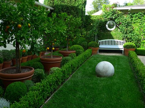 .concrete ball on grassy hedgerow-lined rectangular space with garden ...