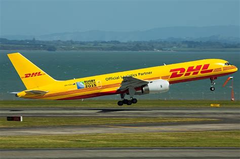 a dhl airplane taking off from an airport runway with the ocean in the ...