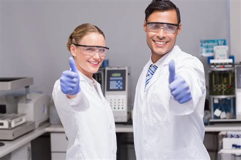 Smiling scientists looking at camera thumbs up in laboratory - Calprotectin