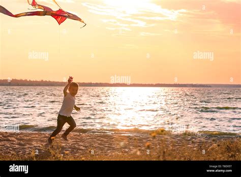 Cute little boy flying kite near river at sunset Stock Photo - Alamy