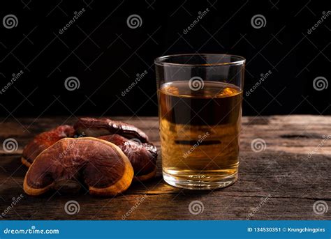 Glass of Reishi Tea and Dried Lingzhi Mushroom on Dark Wooden Floor ...