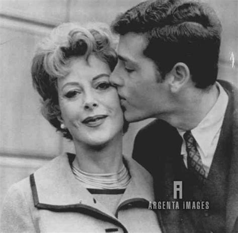 a black and white photo of a man kissing a woman's face on the cheek