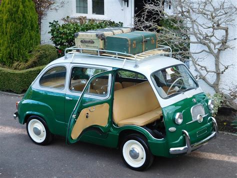 an old green and white car with luggage on it's roof rack, parked in ...