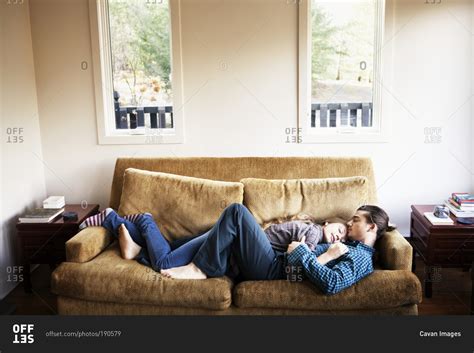 Couple cuddling and sleeping on couch together stock photo - OFFSET