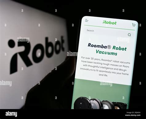 Person holding smartphone with web page of US technology company iRobot ...