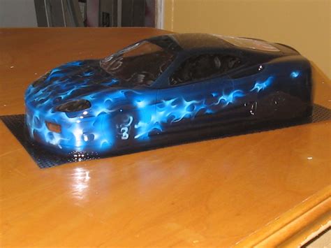 a cake shaped like a car on top of a wooden table with blue flames ...