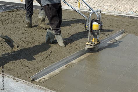 Smoothing fresh concrete with gas powered vibrating screed machine ...