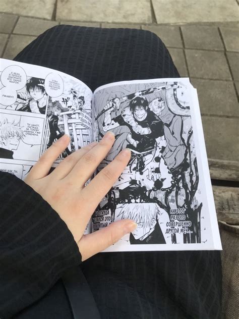 a person is reading a comic book on their lap and holding it in their hand