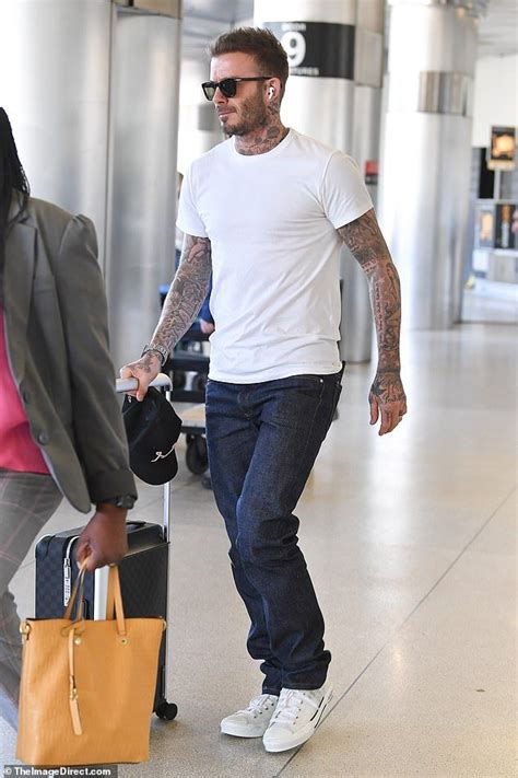 David Beckham displays his heavily-tatted arms as he arrives in Miami ...