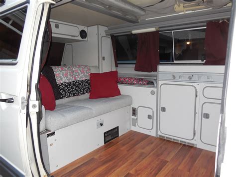 Cozy Camper Van Interior with Wood Flooring and Red Pillows