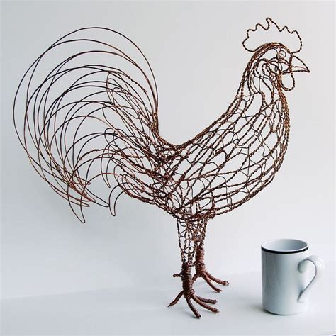 a wire sculpture of a rooster next to a coffee cup