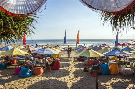 Indonesia, Bali, Denpasar, Tourists under colorful sunshades at Kuta ...