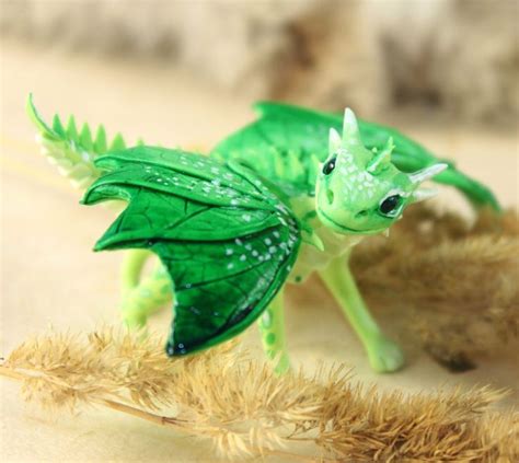 a small green toy dragon sitting on top of a pile of dried grass