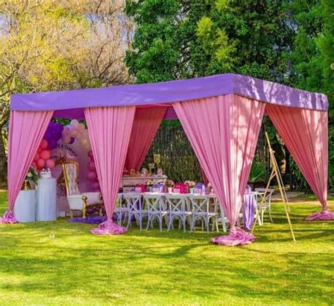 a pink tent set up in the middle of a field with tables and chairs under it