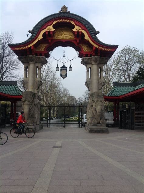 a person riding a bike in front of a gated area with statues on it